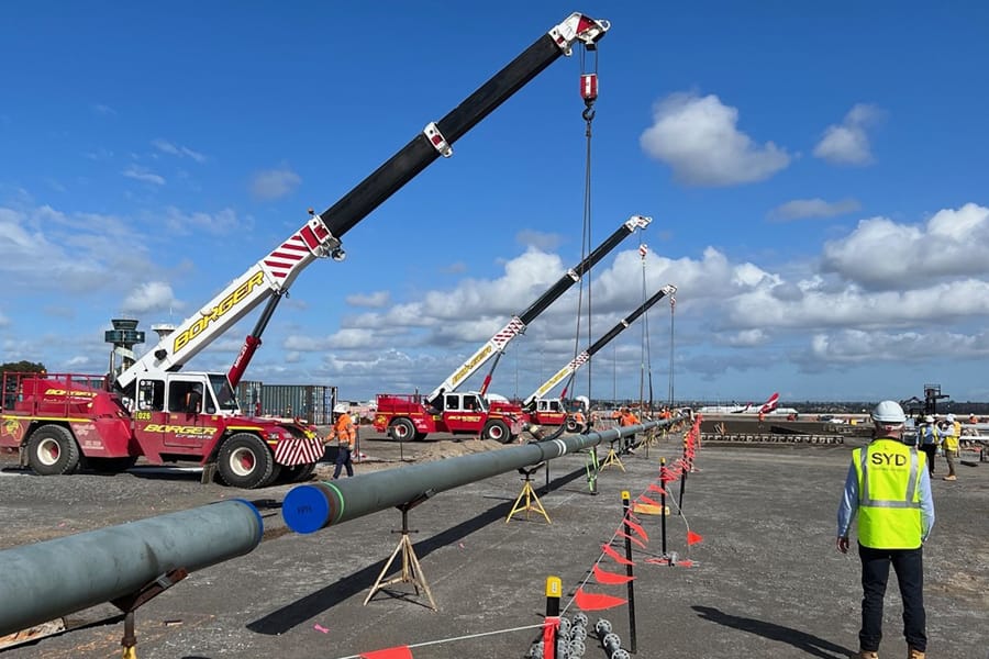 Cranes lifting large fuel pipelines at Sydney Airport construction site
